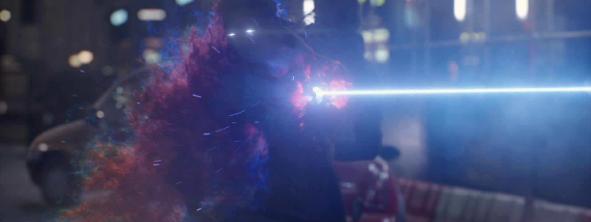 A figure dissolves into red and blue particles as an energy beam crosses a night street, from Men in Black: International.